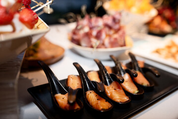 delicacy, salmon meat on black teaspoons