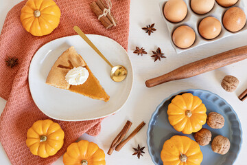 Pumpkin pie baking ingredients with pumpkins, nuts, seasonal spices and piece of pie. Thanksgiving and autumn holidays celebration concept. Top view, flatlay