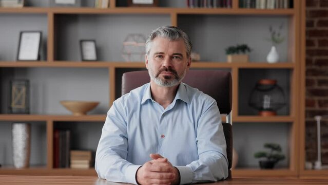 Smiling businessman talking to web camera sitting in office. Recording vlog, online video conference, video call, online education. Job interview, online training. Webcam view.