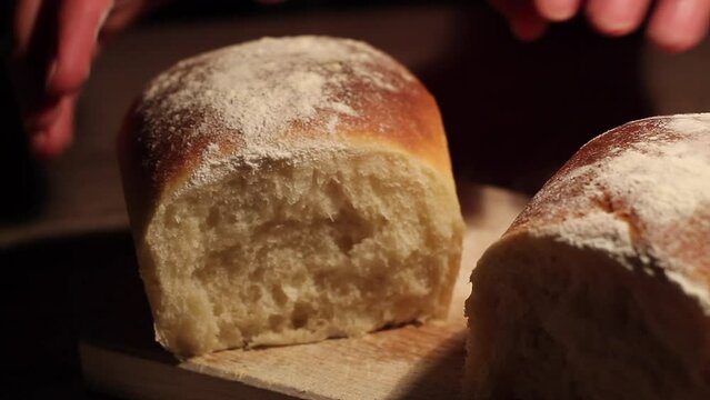 Cook separates the bread while the bread is smoking , moody yellow light focus on bread surface and texture. Cook squishes the bread. Male cook