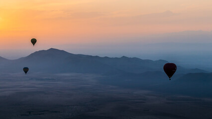 hot air balloon flying over the Moroccan desert and the atlas mountains at sunrise