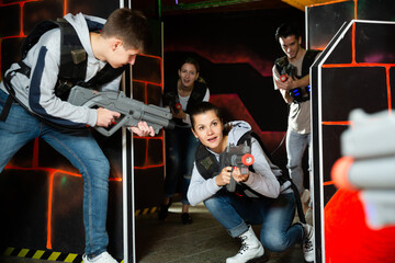 Fototapeta na wymiar Ordinary Laser tag players young mens and womens playing in teams in dark laser tag station. High quality photo
