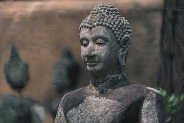 Ancient old ruin Head of Buddha statue carved from sandstone was destroyed and abandoned left in the Wat U Mong Temple.