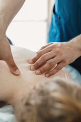 Men's hands make a therapeutic neck massage for a girl lying on a massage couch.