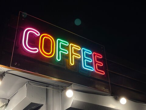 Low angle shot of a colorful coffee shop neon sign in the dark
