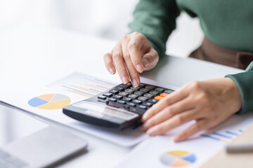 Close up of businesswoman Accounting using calculating income-expenditure and analyzing real estate investment data report Financial and tax systems concept.	