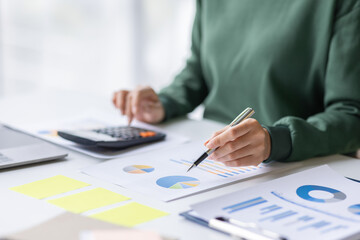 Close up of businesswoman Accounting using calculating income-expenditure and analyzing real estate investment data report Financial and tax systems concept.	