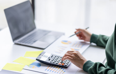 Close up of businesswoman Accounting using calculating income-expenditure and analyzing real estate investment data report Financial and tax systems concept.	