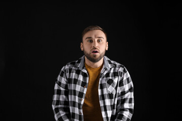 Fototapeta premium Portrait of emotional young man on black background. Personality concept