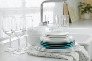 Different clean dishware and glasses on countertop near sink in kitchen