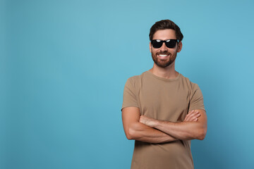 Portrait of smiling bearded man with stylish sunglasses on light blue background. Space for text