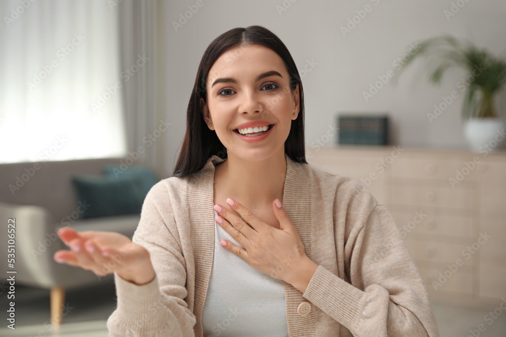 Wall mural Beautiful young woman conducting webinar in room, camera view