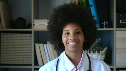 Happy female african american doctor with stethoscope at her clinic. Confident frontline heathcare worker smiling while looking at camera. Young doctor wearing lab coat with stethoscope at hospital