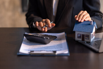 Close up house model with business man signs a purchase contract or mortgage for a home, buy and sell home insurance concerning mortgage loan Real estate concept.