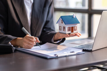 Close up house model with business man signs a purchase contract or mortgage for a home, buy and...