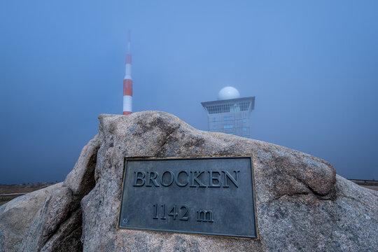 Schild mit H&ouml;henangaben des Brocken, mit Fernsehturm und Brockenhotel im Hintergrund