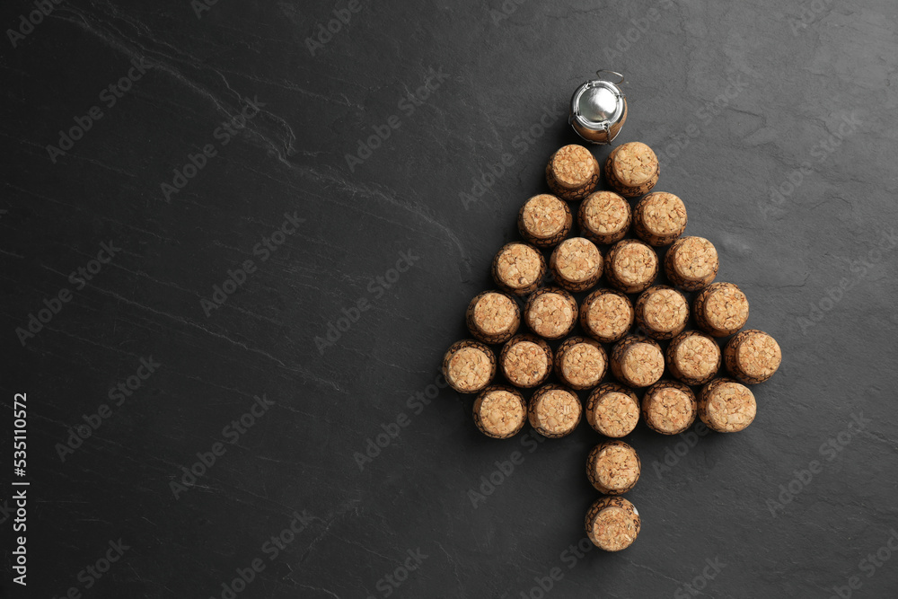 Sticker Christmas tree made of sparkling wine corks on black background, flat lay. Space for text