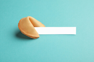 Tasty fortune cookie with predictions on light blue background. Space for text