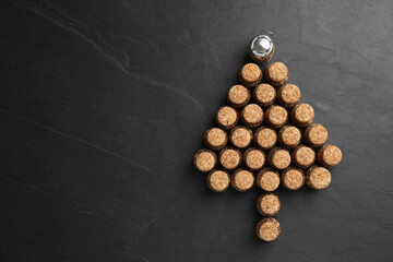 Christmas tree made of sparkling wine corks on black background, flat lay. Space for text