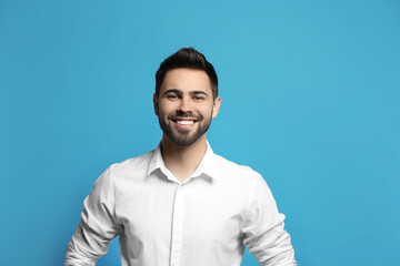 Young man laughing on light blue background. Funny joke