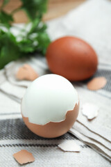 Boiled eggs and pieces of shell on kitchen towel, closeup