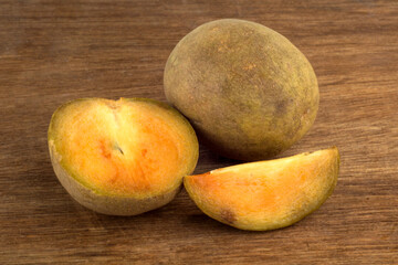 sapodilla fruit with pieces of sapodilla fruit on a wooden background