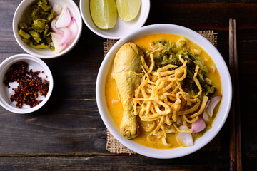 Northern Thai food (Khao Soi), Spicy curry noodles soup with chicken on wooden background, Local Thai food
