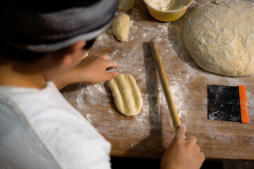 Male baker hands with flour dough preparing food on wooden table. Baking process, culinary, recipe, home baking.