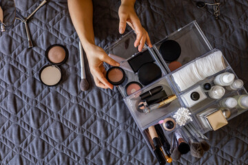 Woman hands tidying up putting powder container into acrylic storage box makeup products placement