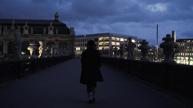 young woman in a black coat walking over a terrace enjoying the view