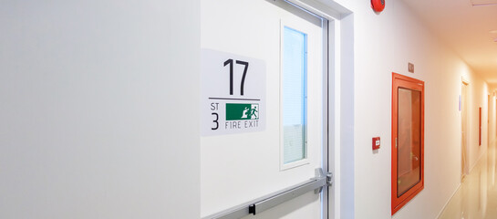 Fire extinguisher system on the wall with Fire Exit door sign for emergency. Stairwell fire for...