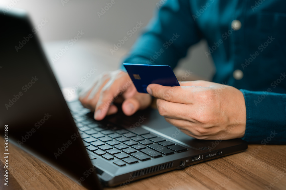 Poster man uses a laptop to register through a credit card to make online purchases. credit card safe onlin