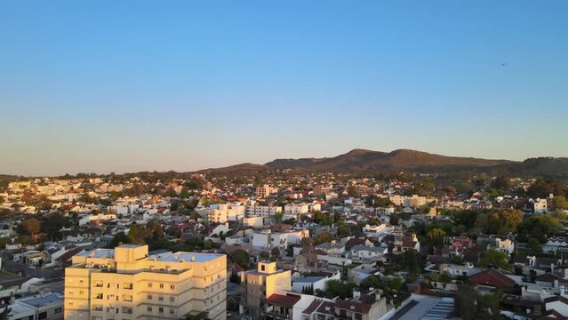 Aereal view of a small town with hills in the horizon at golden hour in Tandil, Argentina. Tilt up shot