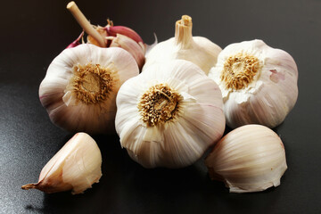 Portion of garlic bulbs on the black table under side light.