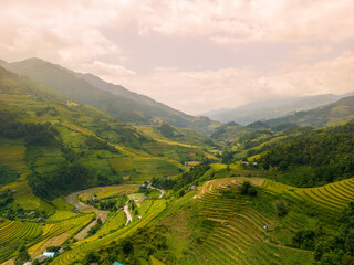 Fototapeta premium Aerial view of golden rice terraces at Mu cang chai town near Sapa city, north of Vietnam. Beautiful terraced rice field in harvest season in Yen Bai, Vietnam