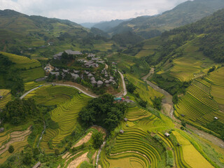 Obraz premium Aerial view of golden rice terraces at Mu cang chai town near Sapa city, north of Vietnam. Beautiful terraced rice field in harvest season in Yen Bai, Vietnam