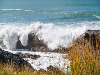 Waves breaking over and around rocky base Mount Maunganui
