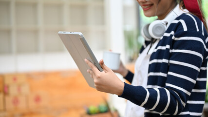 cropped, A young Asian female with headphones, holding a portable tablet.