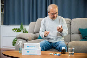 Asian worried senior man with medicine pills to taking on table in the living room, old man buy...