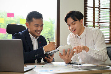 Handsome Asian businessman having a nice conversation with his colleague during work together.