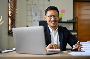 Fototapeta na wymiar Successful and professional adult Asian businessman in formal suit working at his office desk.