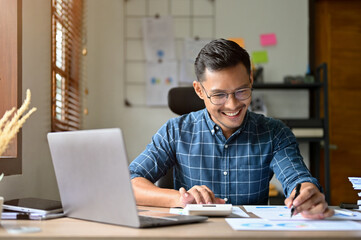Smart and happy adult Asian businessman or male accountant working on his financial data