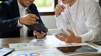 Smart Asian male financial counselors using calculator, working together. cropped image