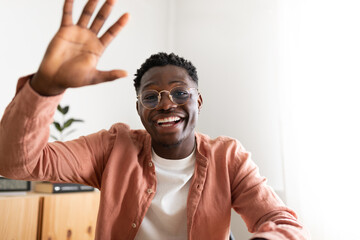 African american young man looking at camera waving hand saying hello during video call.