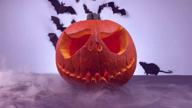 Scary lighting pumpkin on wooden table. Halloween decoration on wooden table covered by fog. Ghost smoke.