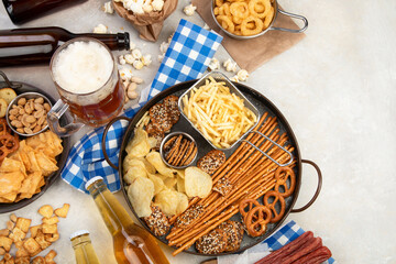 Assortment of beer and salty snacks on light background.