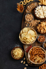 Assortment of salty snacks on dark background.