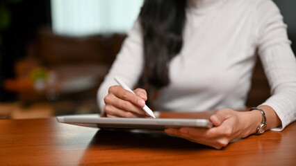 Fototapeta na wymiar Beautiful Asian female using a digital tablet at her desk. cropped image