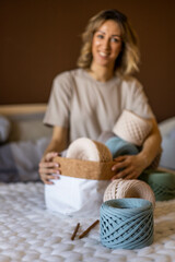 Portrait smiling blonde woman design holding pile of multicolored hank reel ribbon yarn