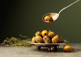 Spicy green olives are poured with olive oil with spices.